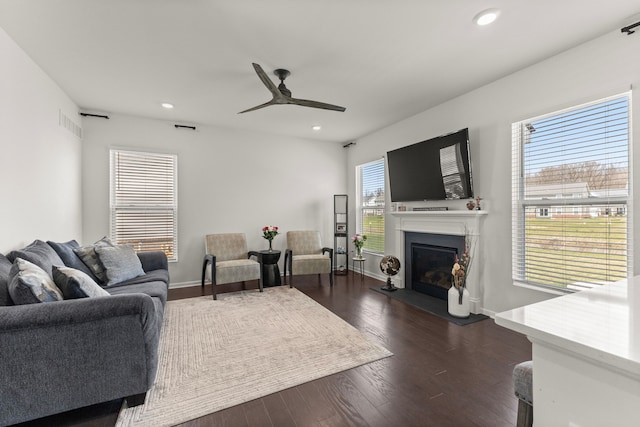 living area featuring dark wood-style flooring, ceiling fan, a glass covered fireplace, recessed lighting, and visible vents