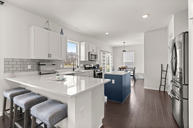 kitchen featuring a center island, recessed lighting, a sink, backsplash, and stainless steel appliances