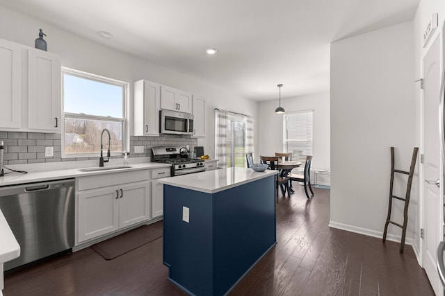 kitchen with a kitchen island, light countertops, tasteful backsplash, a sink, and stainless steel appliances