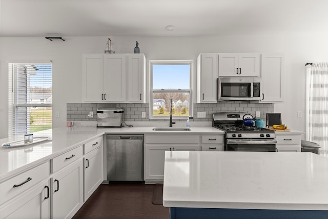 kitchen with a sink, appliances with stainless steel finishes, backsplash, and light countertops