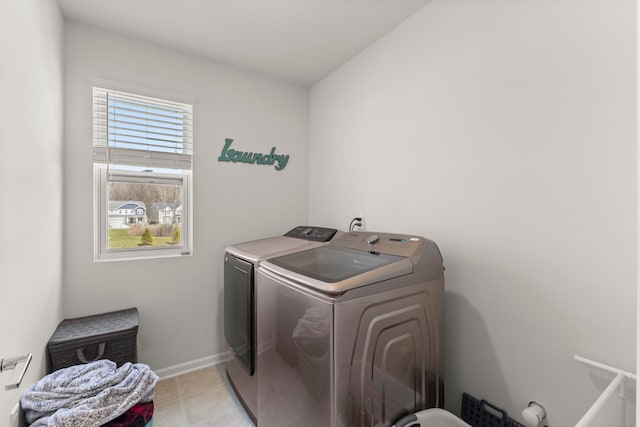 laundry area featuring laundry area, washer and clothes dryer, baseboards, and light tile patterned floors