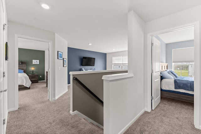 hallway with light colored carpet, recessed lighting, baseboards, and an upstairs landing