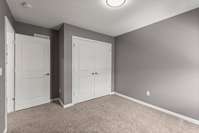 unfurnished bedroom with a closet, baseboards, carpet flooring, and visible vents