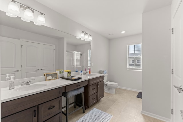 bathroom with a sink, toilet, double vanity, baseboards, and a stall shower