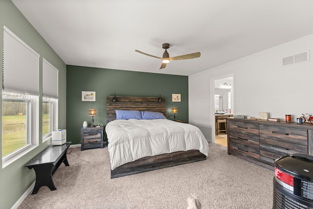 carpeted bedroom featuring ceiling fan, baseboards, visible vents, and ensuite bathroom
