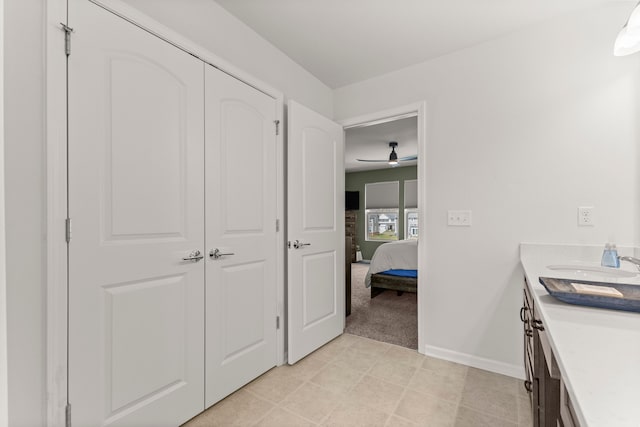 ensuite bathroom with ceiling fan, vanity, baseboards, tile patterned floors, and ensuite bath
