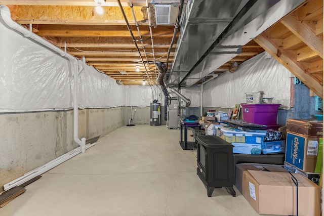 unfinished basement with visible vents, heating unit, and water heater