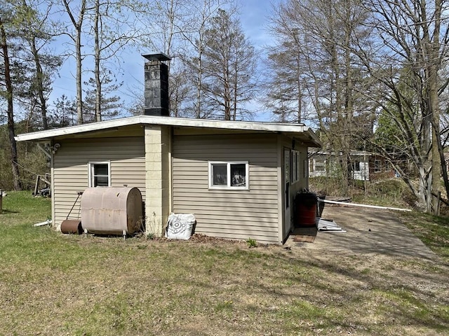rear view of property featuring a lawn, heating fuel, and a chimney