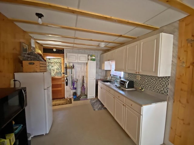 kitchen featuring backsplash, light countertops, a toaster, white cabinets, and freestanding refrigerator