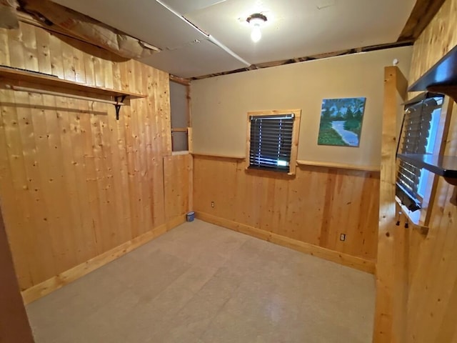 finished below grade area featuring baseboards, tile patterned floors, wainscoting, and wood walls