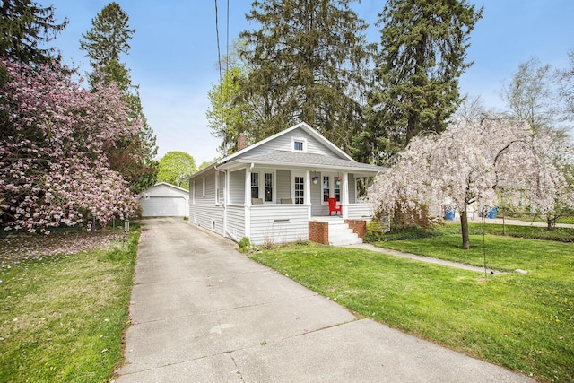 view of front of home with covered porch, a chimney, a front yard, an outbuilding, and a detached garage