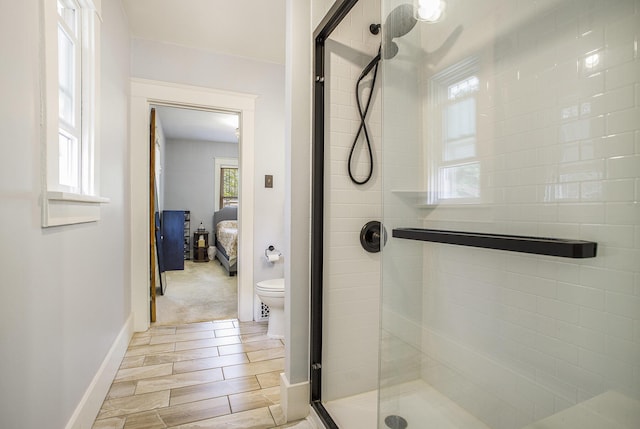 ensuite bathroom featuring baseboards, connected bathroom, a stall shower, and toilet