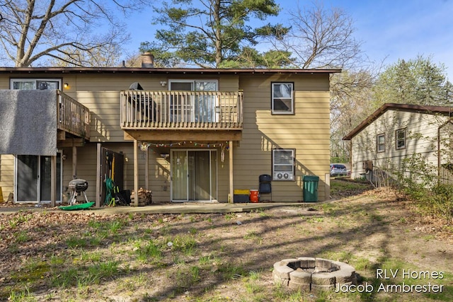 back of house featuring fence, a fire pit, and a chimney