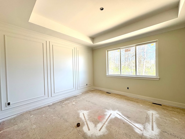 empty room with a raised ceiling, baseboards, and visible vents