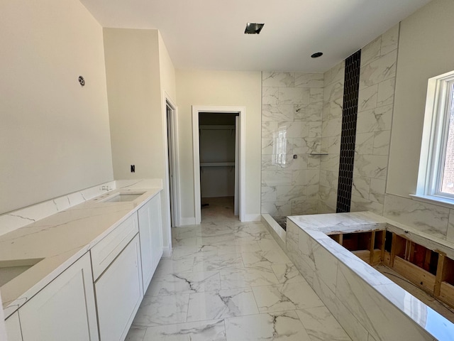 bathroom with a sink, baseboards, marble finish floor, a spacious closet, and a marble finish shower
