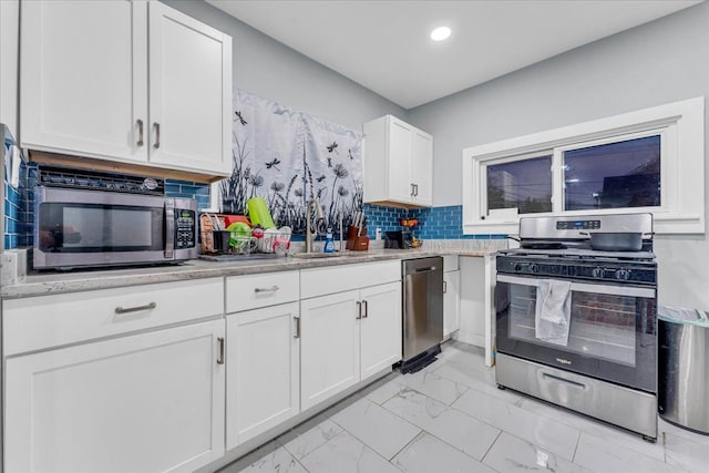kitchen with backsplash, a sink, white cabinets, marble finish floor, and stainless steel appliances