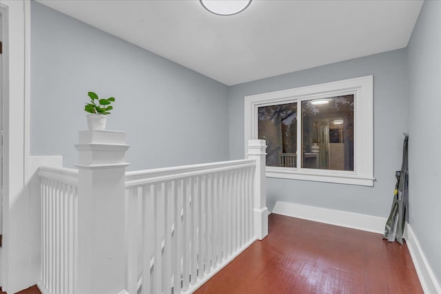 corridor with baseboards, wood finished floors, and an upstairs landing