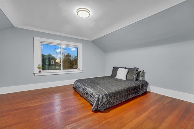 bedroom with baseboards, vaulted ceiling, and wood finished floors