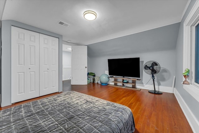bedroom featuring baseboards, visible vents, wood finished floors, and vaulted ceiling