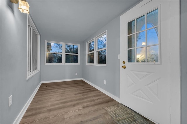 doorway to outside featuring baseboards and wood finished floors