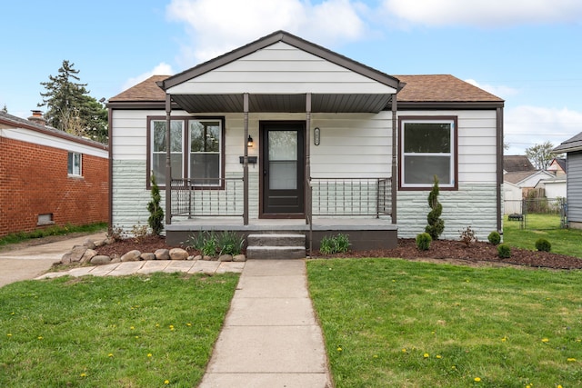 bungalow-style house featuring roof with shingles, covered porch, and a front yard
