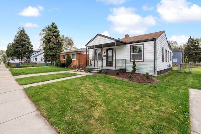 view of front facade with covered porch, fence, a chimney, and a front lawn