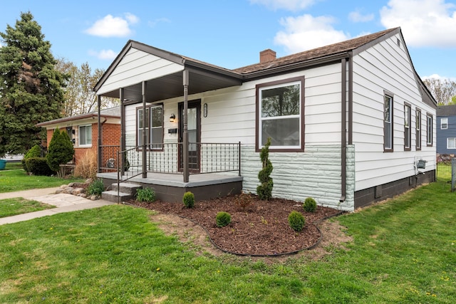 view of front of property featuring a porch, a front yard, and a chimney