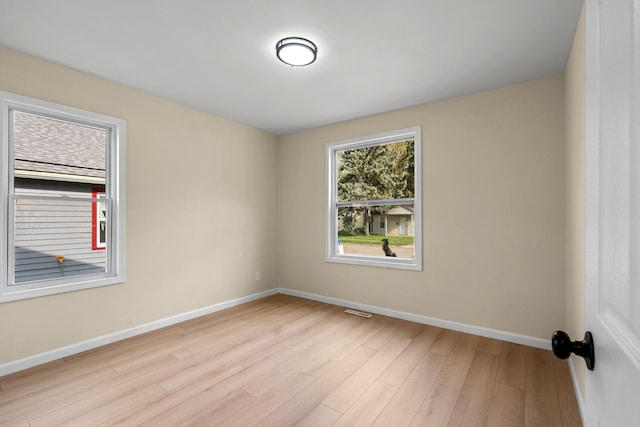 empty room with baseboards, light wood finished floors, and visible vents