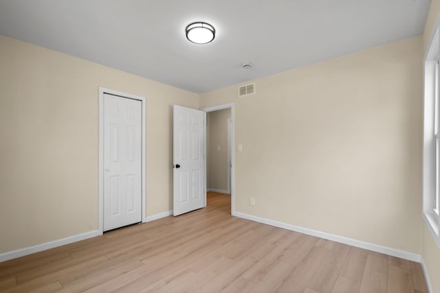 unfurnished bedroom with visible vents, baseboards, a closet, and light wood-type flooring