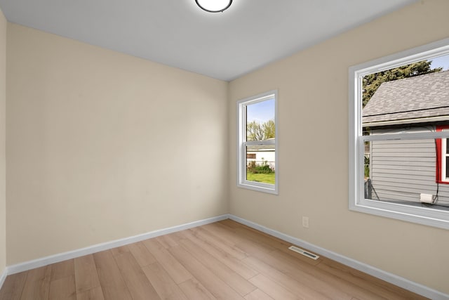 empty room featuring baseboards, visible vents, and wood finished floors