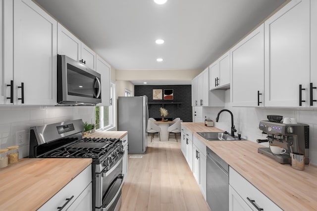 kitchen with recessed lighting, a sink, butcher block counters, and stainless steel appliances