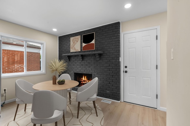 dining area featuring light wood-style floors, a brick fireplace, recessed lighting, and visible vents