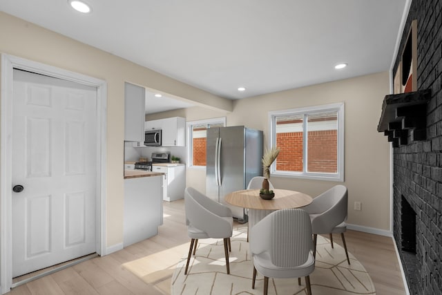 dining room with light wood-style floors, recessed lighting, baseboards, and a fireplace
