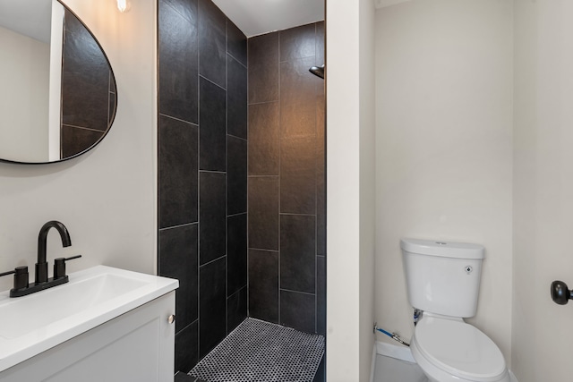 full bath featuring vanity, toilet, and tiled shower