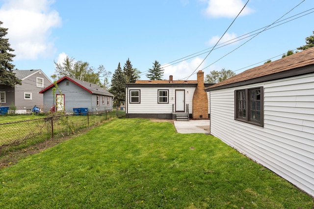 rear view of property with fence, a chimney, a patio area, entry steps, and a lawn
