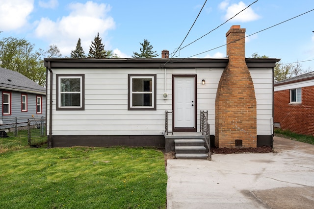 view of front of home with fence, a front yard, and a chimney