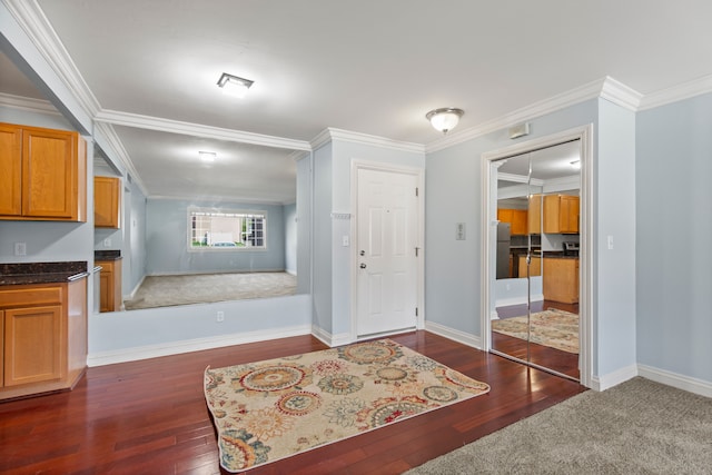 entryway with dark wood-type flooring, ornamental molding, and baseboards