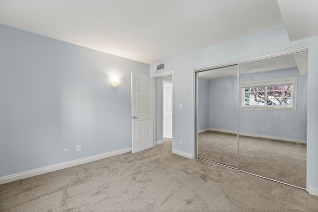 unfurnished bedroom featuring visible vents, carpet, baseboards, and a closet