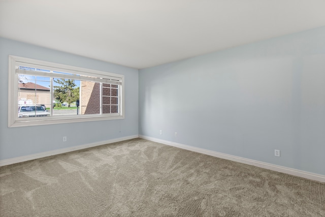 carpeted empty room featuring baseboards