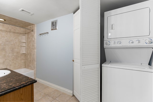 laundry room with light tile patterned flooring, laundry area, baseboards, visible vents, and stacked washer and clothes dryer
