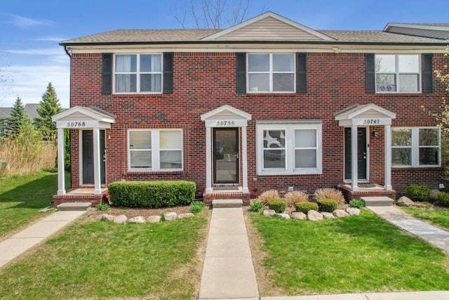 multi unit property with a front lawn and brick siding