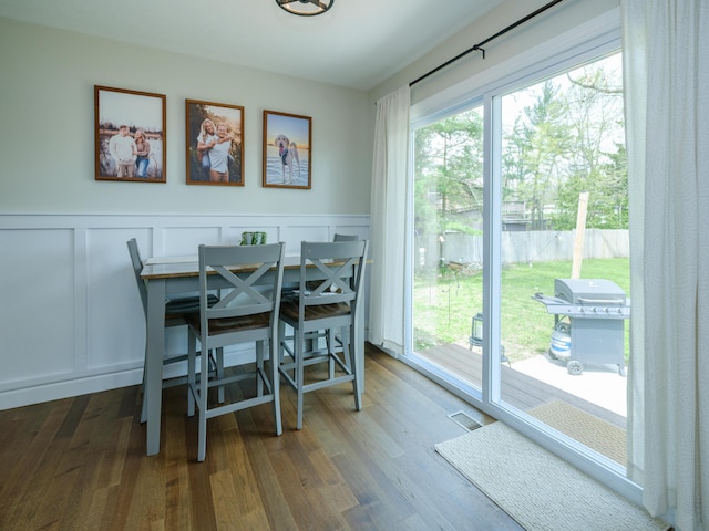 dining space featuring a wainscoted wall, a decorative wall, wood finished floors, and a wealth of natural light