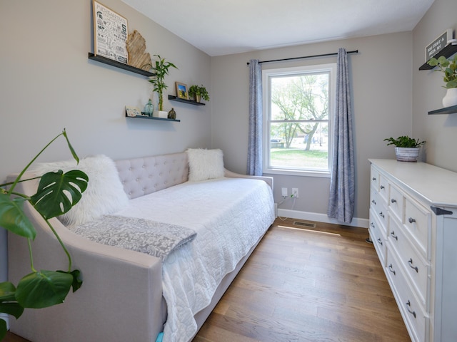 bedroom with baseboards, visible vents, and wood finished floors