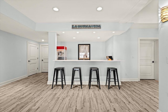 kitchen featuring baseboards, a breakfast bar area, recessed lighting, and wood finished floors