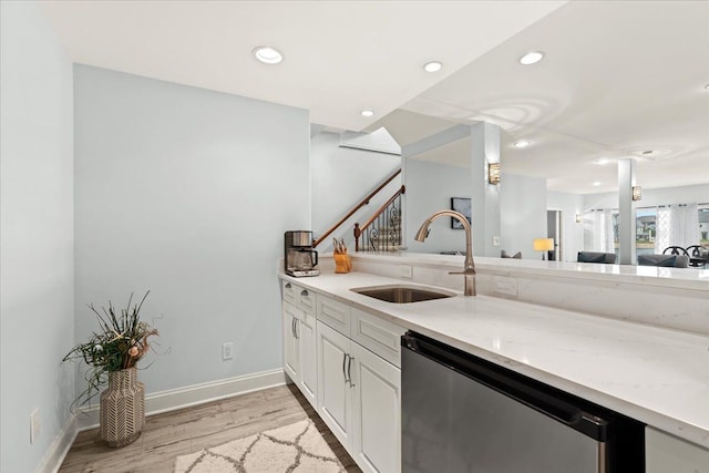 kitchen featuring dishwasher, light wood-style flooring, baseboards, and a sink