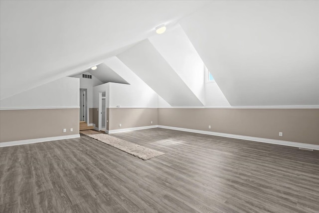 additional living space featuring vaulted ceiling, baseboards, visible vents, and wood finished floors