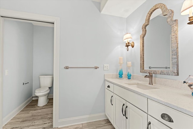 bathroom with vanity, toilet, baseboards, and wood finished floors