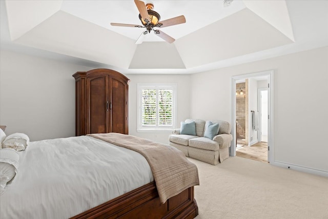 bedroom featuring a ceiling fan, a tray ceiling, connected bathroom, and light colored carpet