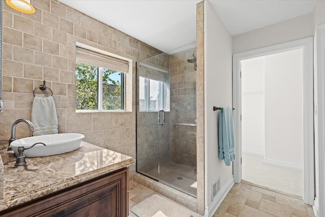 full bathroom with a stall shower, stone tile flooring, tile walls, visible vents, and baseboards