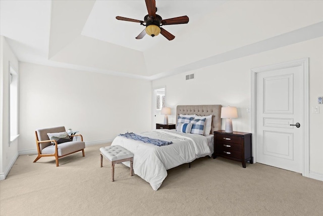bedroom with visible vents, a raised ceiling, ceiling fan, and light carpet